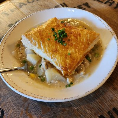 Shredded chicken thighs, onions, carrots, corn, peas and potatoes resting under a melt in your mouth puff pastry